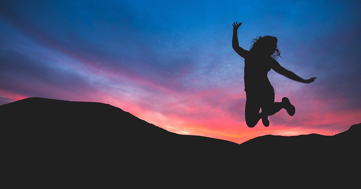 Silhouette of a person jumping against a vibrant sunset sky